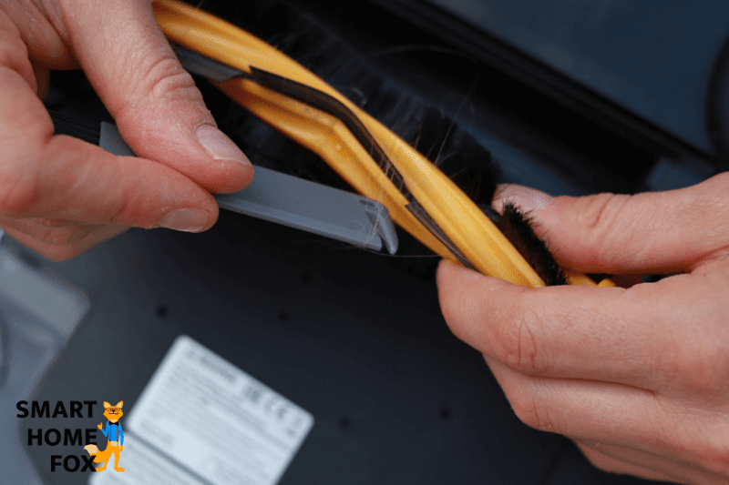 Haare werden bei Ecovacs Deebot OZMO 950 mit Hilfe des Reinigungswerkzeugs aus der Hauptbürste entfernt